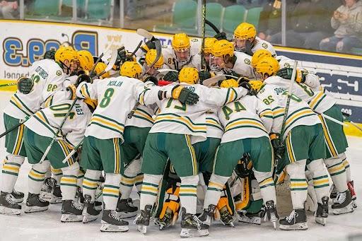 Clarkson men's hockey players huddle in a hug during a game on the ice